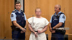 Brenton Tarrant stood in the dock wearing handcuffs and a white prison smock.