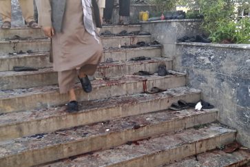 A man walks down blood-stained steps of a mosque following a bombing in Kunduz province, northern Afghanistan, Friday, Oct. 8, 2021. A powerful explosion in a mosque frequented by a Muslim religious minority in northern Afghanistan on Friday has left several casualties, witnesses and the Taliban's spokesman said. (AP Photo/Abdullah Sahil)