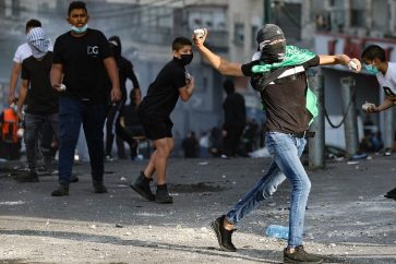 Palestinian youths hurl rocks toward Israeli occupation forces during raid in the Shuafat refugee camp in east Al-Quds on October 12, 2022.